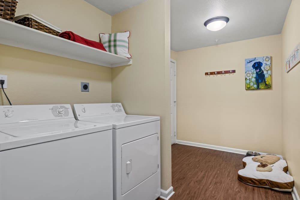 Apartment in-unit laundry room with a washer and dryer and a dog bed at Marquis at Town Centre in Broomfield, CO.