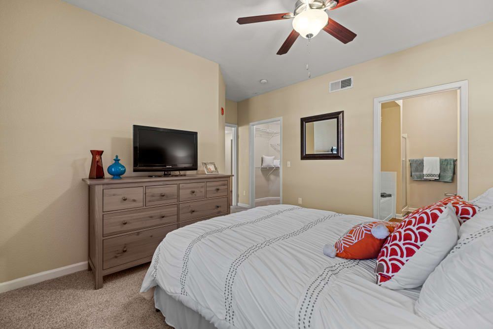 Apartment bedroom with a bed, dresser, television, and ceiling fan at Marquis at Town Centre in Broomfield, CO.