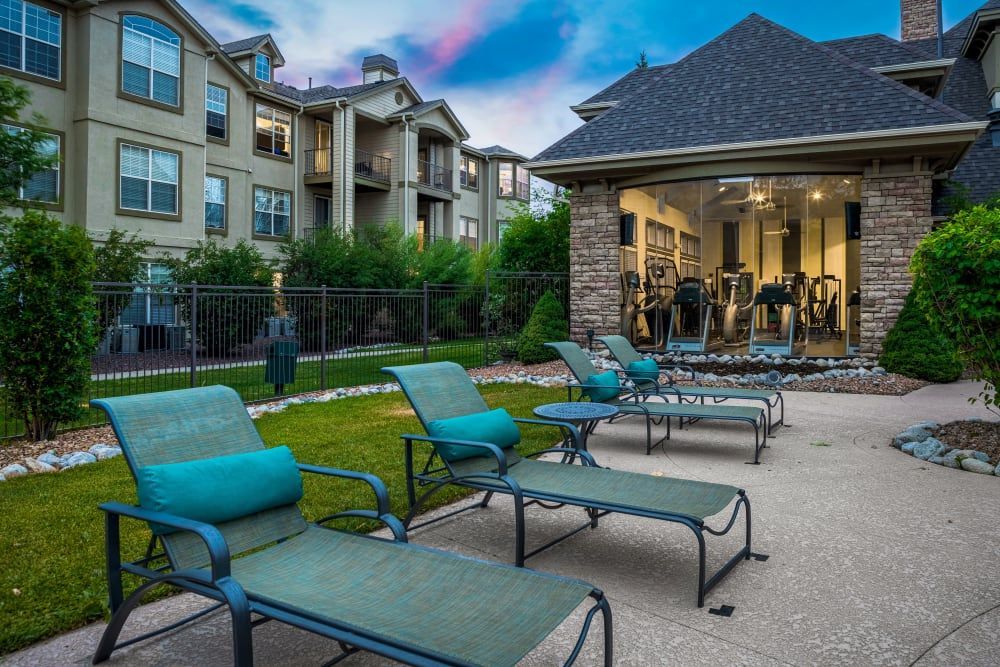 Poolside lounge with lounge chairs and a gym in the background at Marquis at Town Centre in Broomfield, CO.