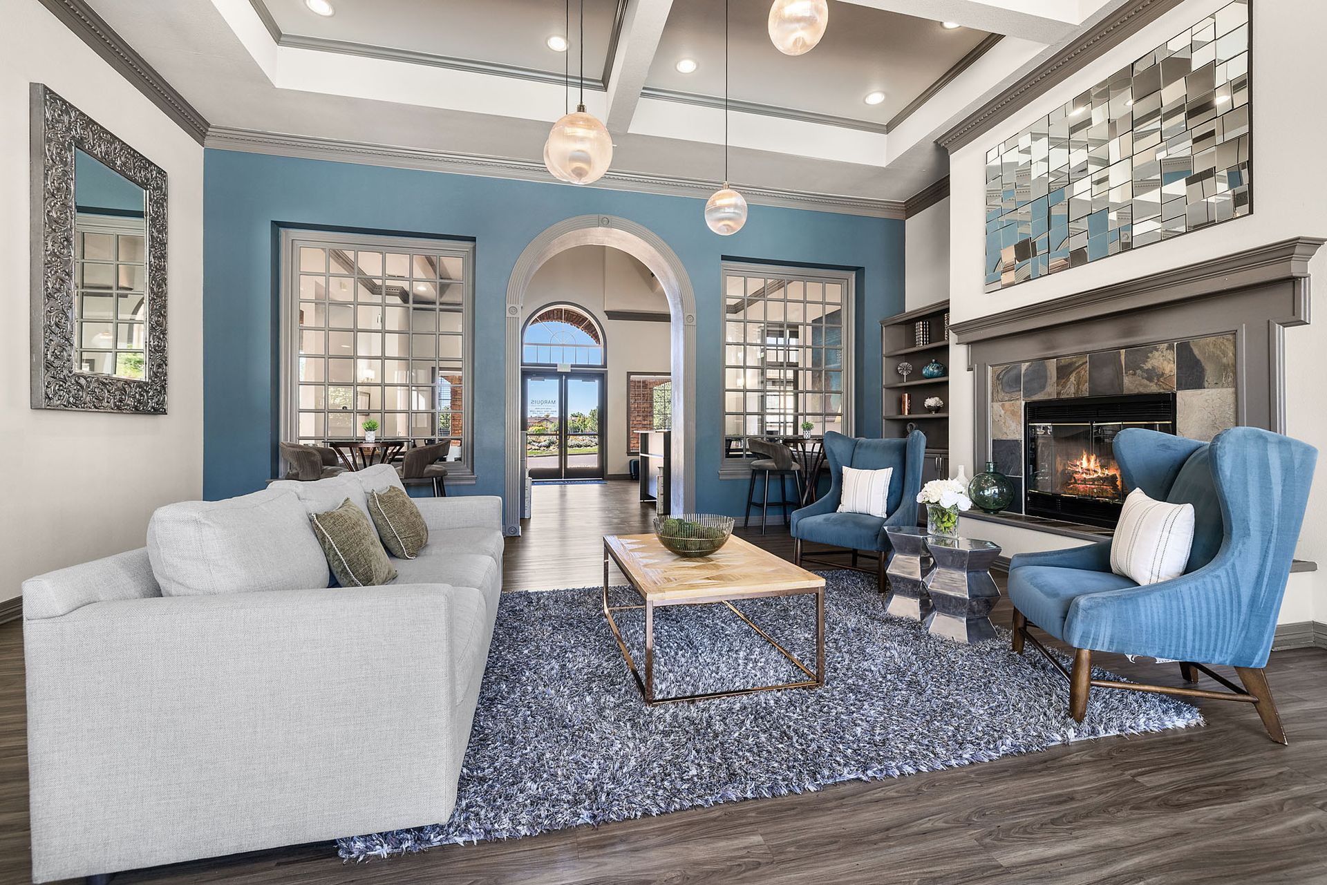 Bright living room with blue walls, white sofa, patterned rug, fireplace, and arched doorway to another room at Marquis at Town Centre in Broomfield, CO