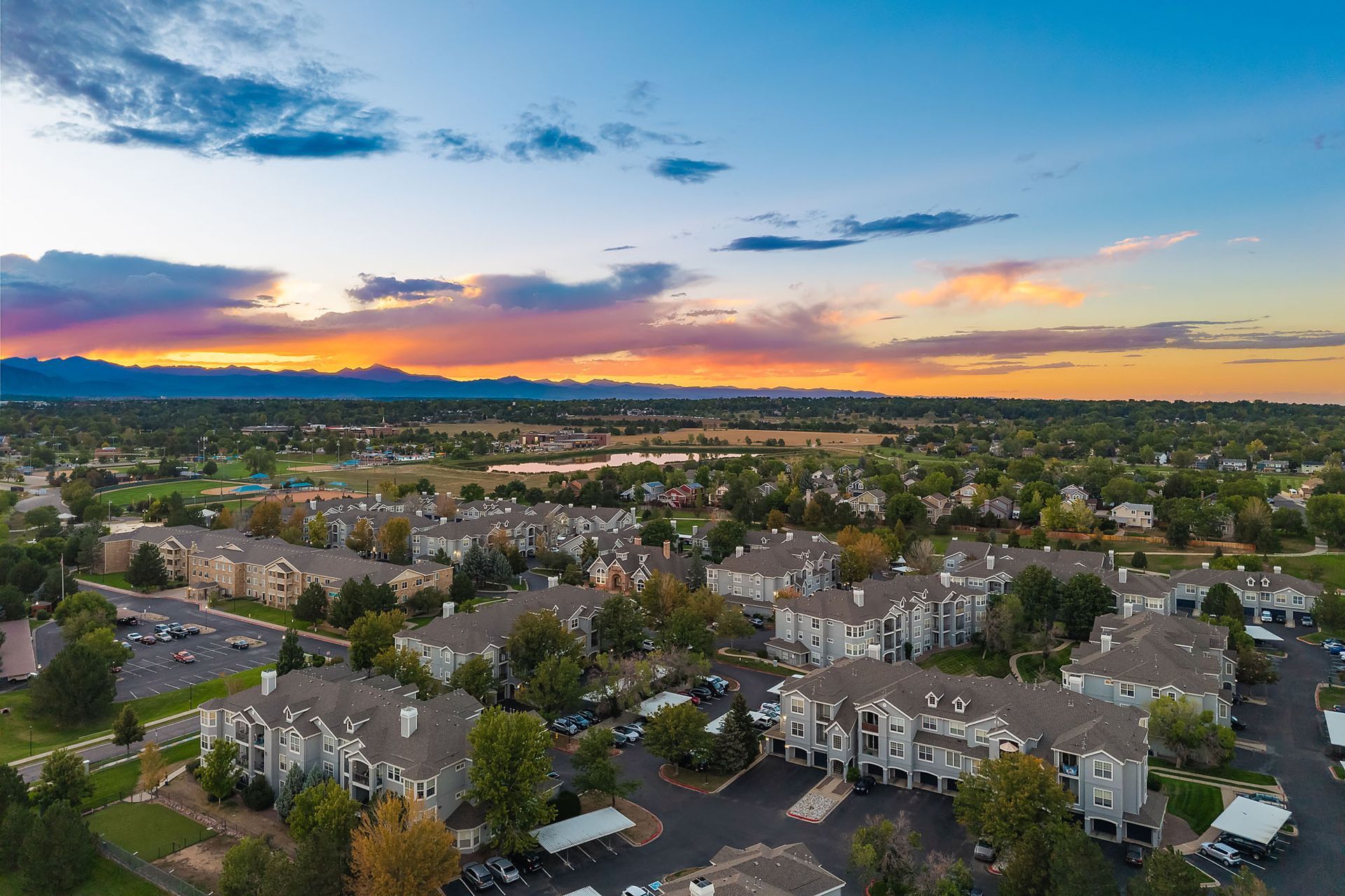 Aerial view of a suburban neighborhood at sunset with colorful sky and distant hills at Marquis at Town Centre in Broomfield, CO