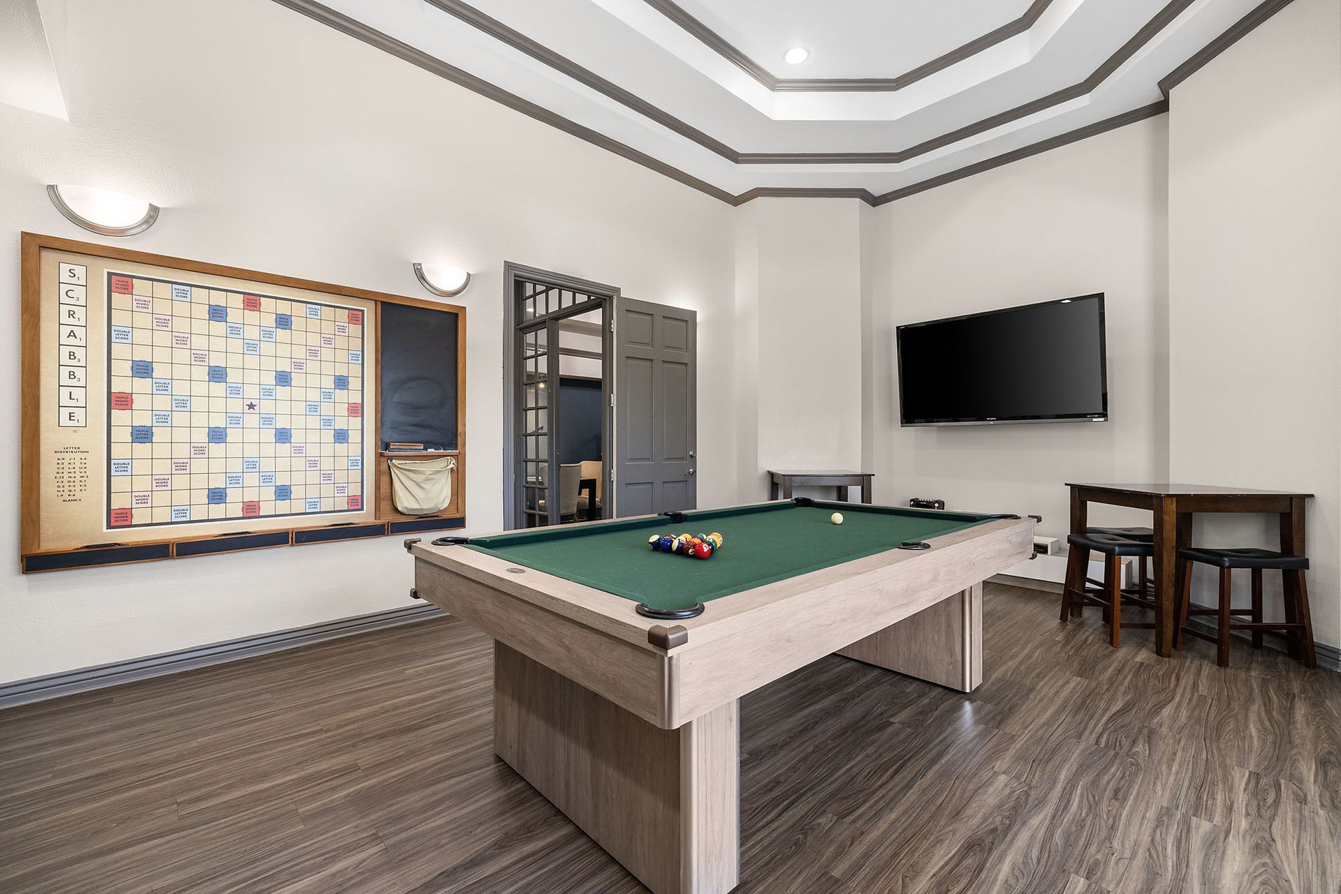 Modern game room with pool table, wall-mounted TV, board game, and small seating area at Marquis at Town Centre in Broomfield, CO