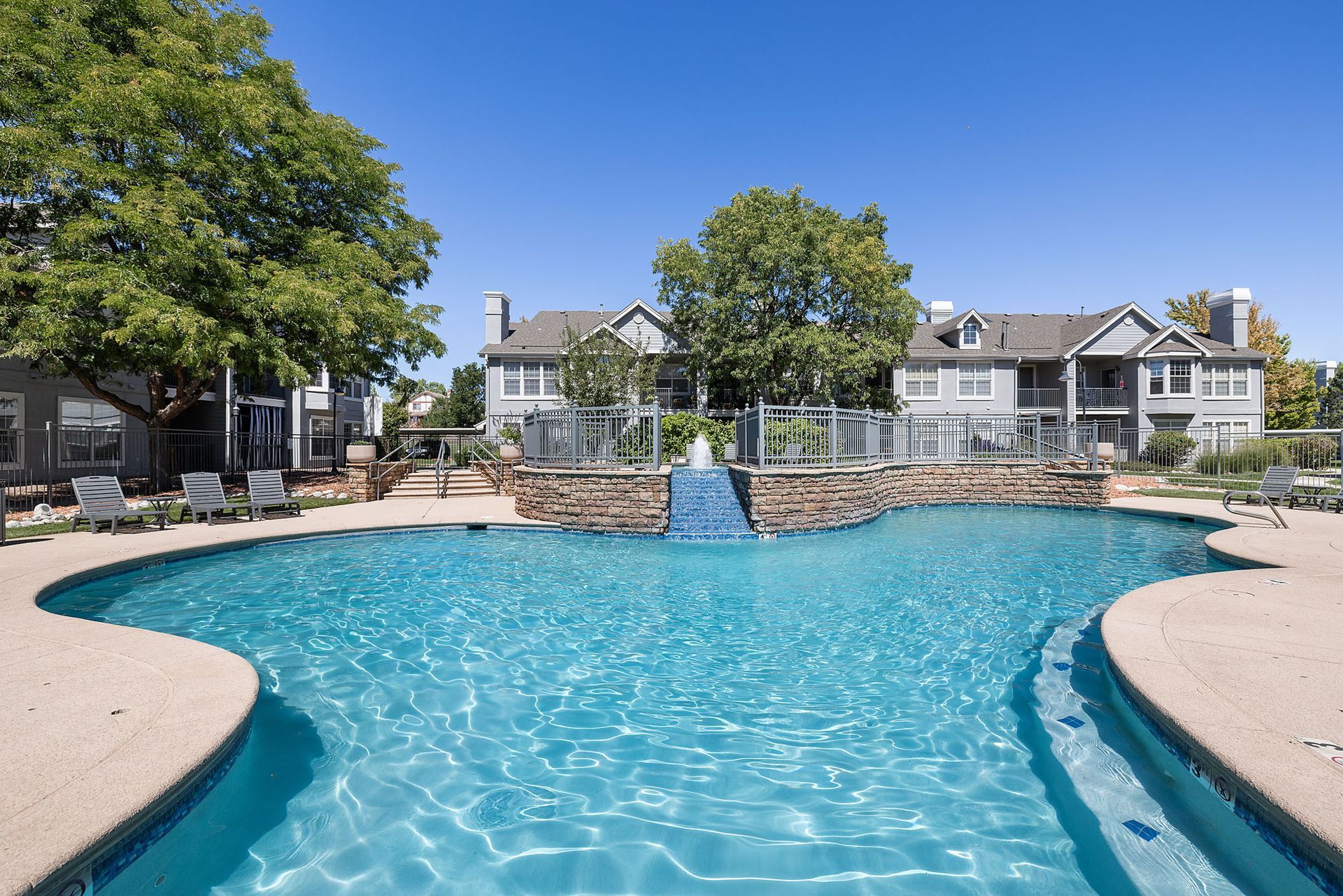 Resort-style swimming pool with blue water and townhouses in the background under a sunny sky at Marquis at Town Centre in Broomfield, CO