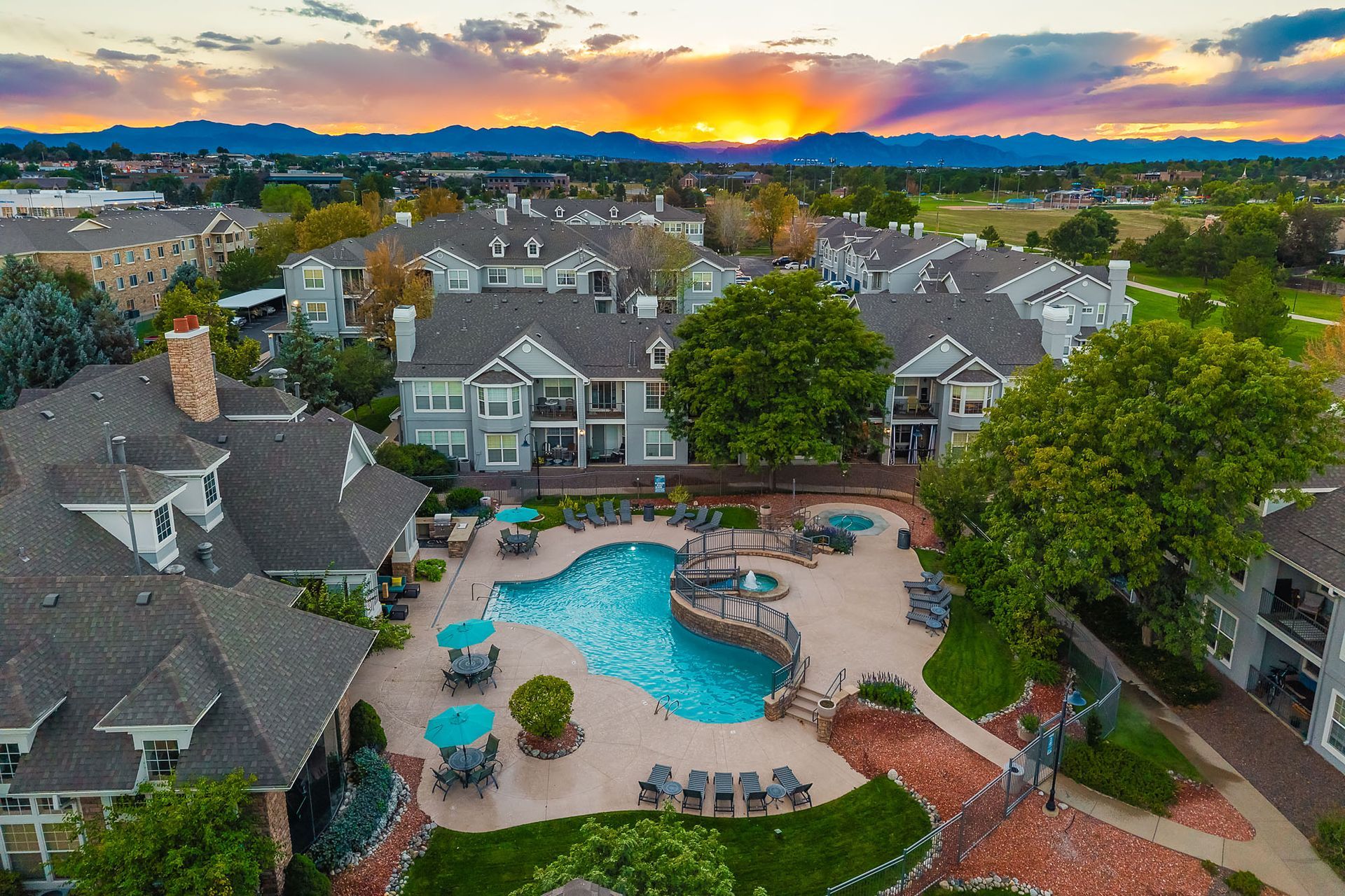 Aerial view of a suburban apartment complex with a swimming pool at sunset at Marquis at Town Centre in Broomfield, CO.