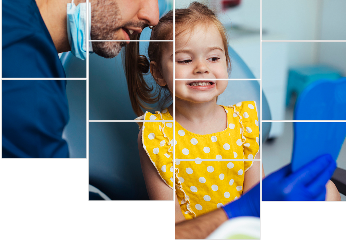 A little girl is sitting in a dental chair looking at her teeth.
