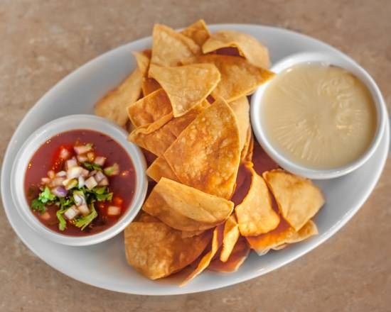 A white plate topped with tortilla chips and two dipping sauces