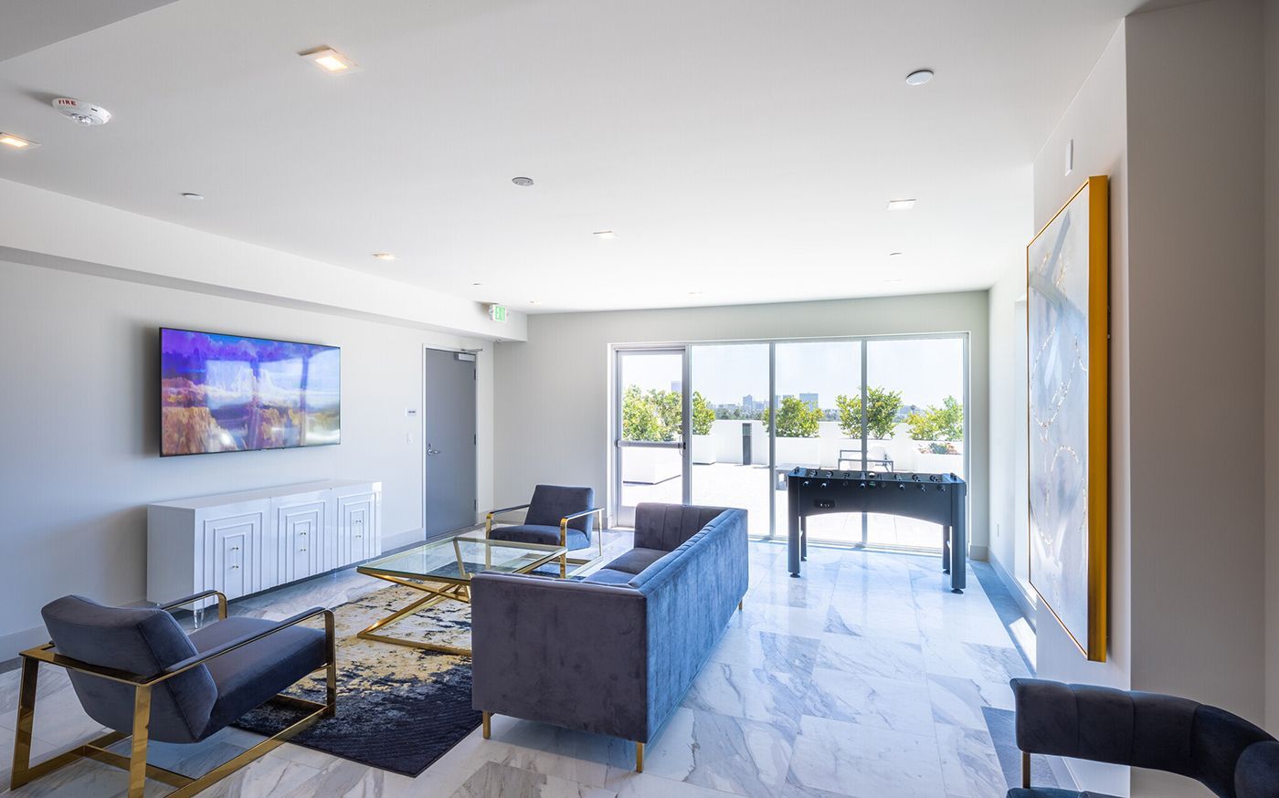 Modern living room with blue furniture, large windows, and marble flooring.