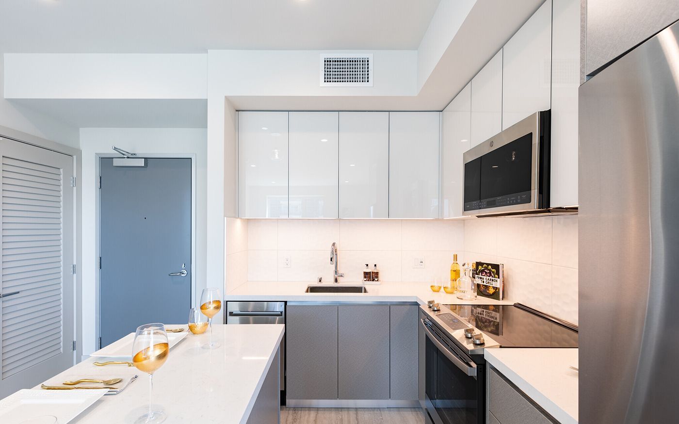 Modern white and gray kitchen with stainless steel appliances.