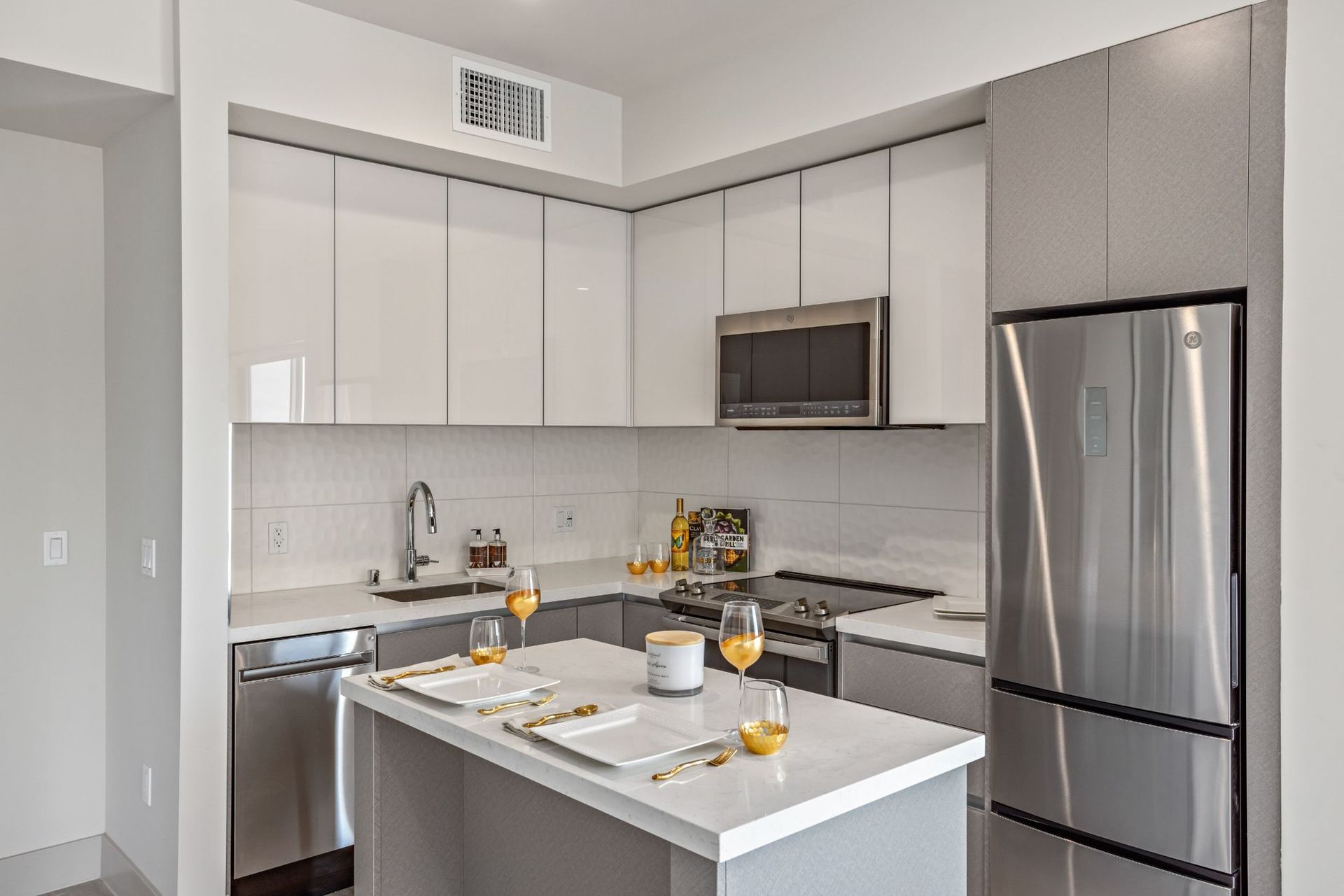 Modern kitchen with white cabinets, stainless steel appliances, and a small island.