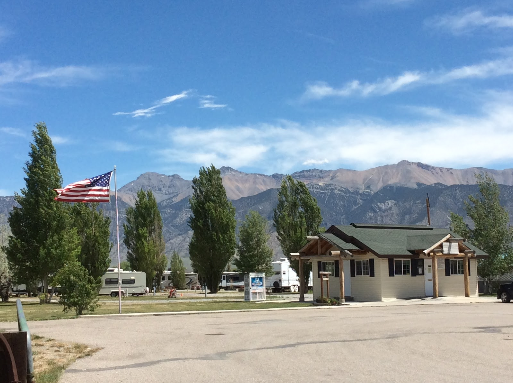 An american flag is flying in front of a building with mountains in the background