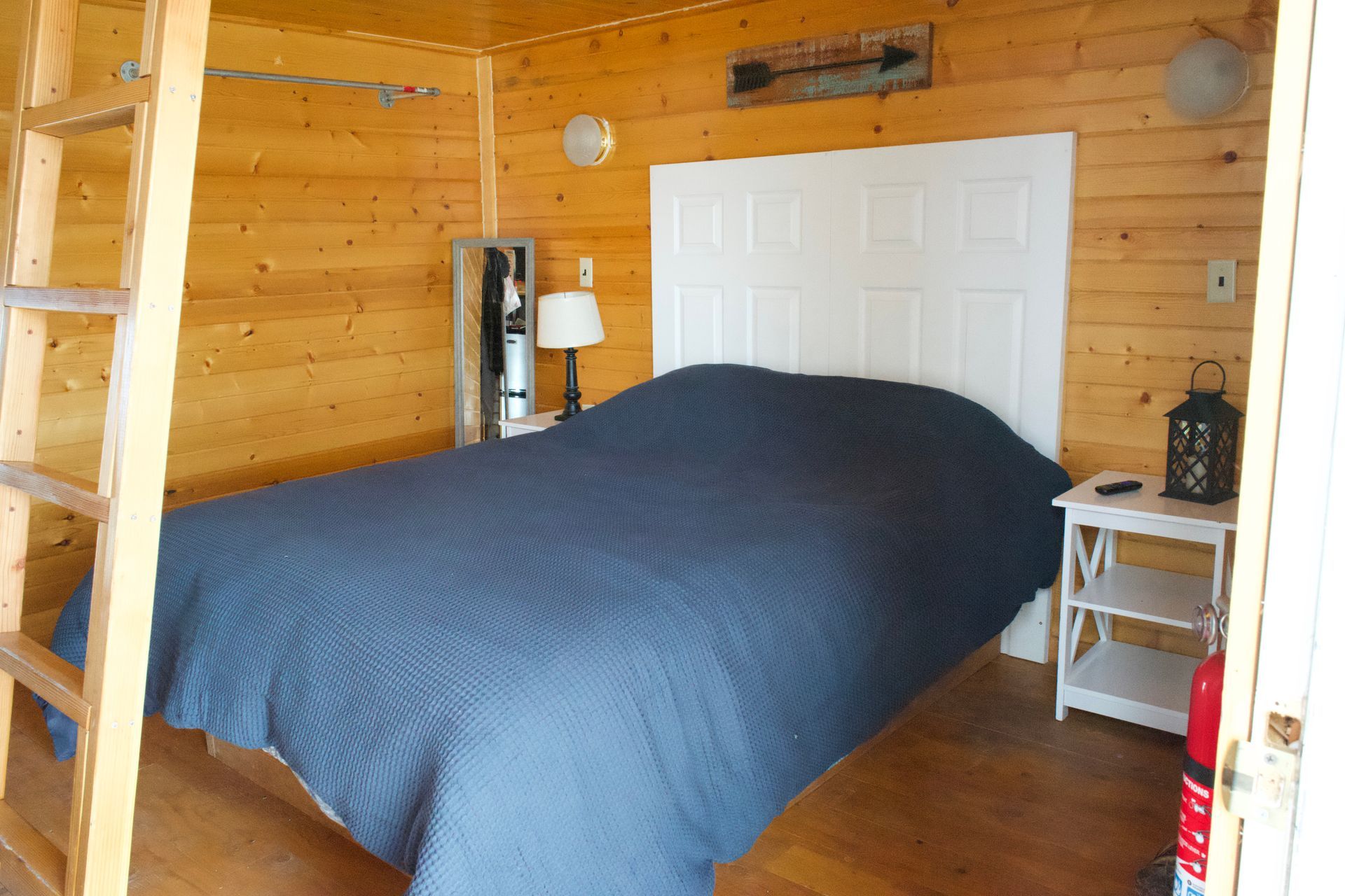 A bedroom with a bed and a ladder in it
