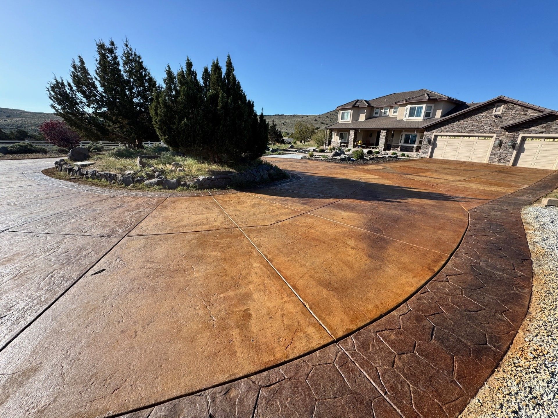 Stamped concrete driveway leading to a suburban house under a clear blue sky