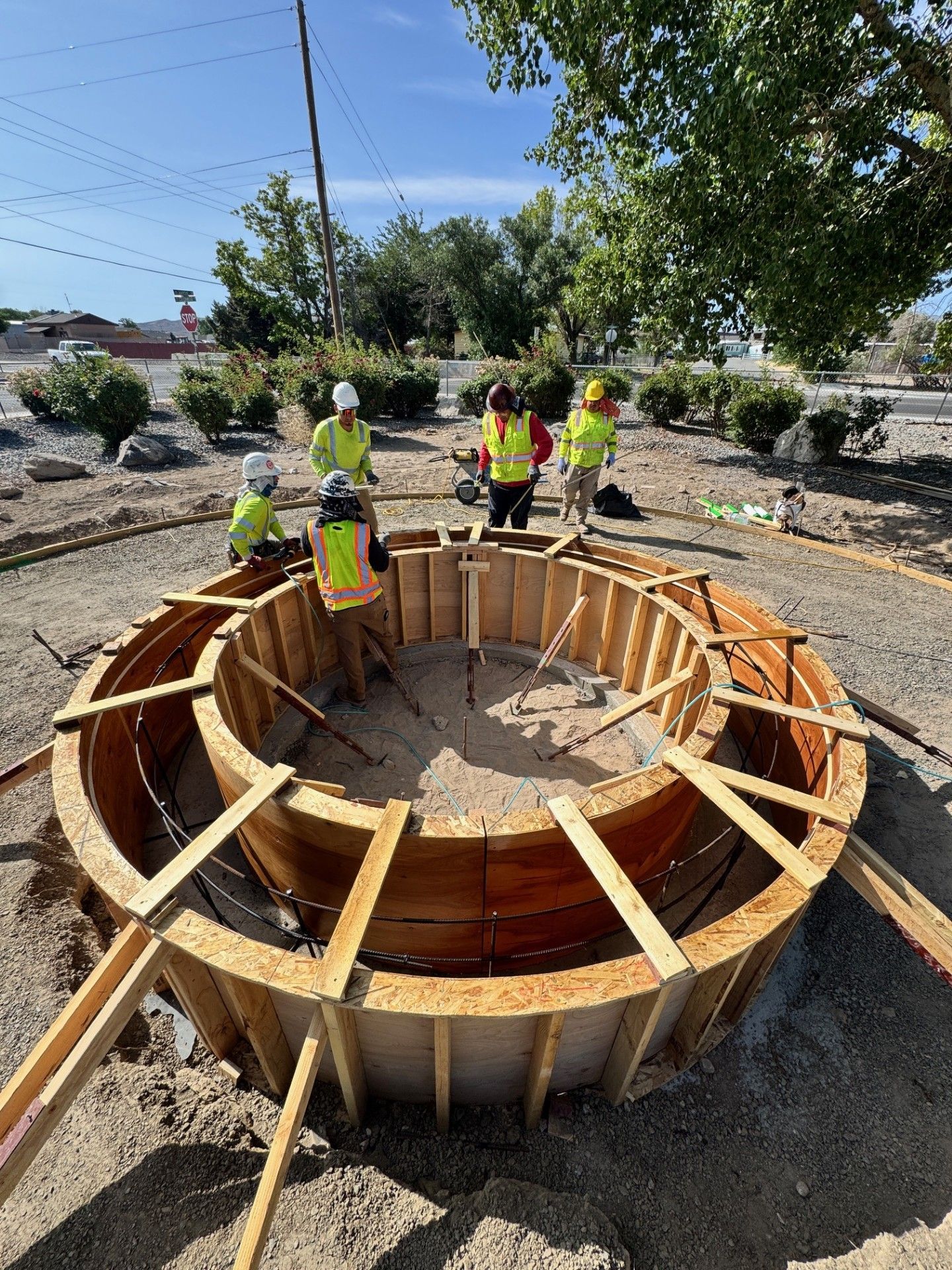 Workers building a large circular wooden form at an outdoor construction site