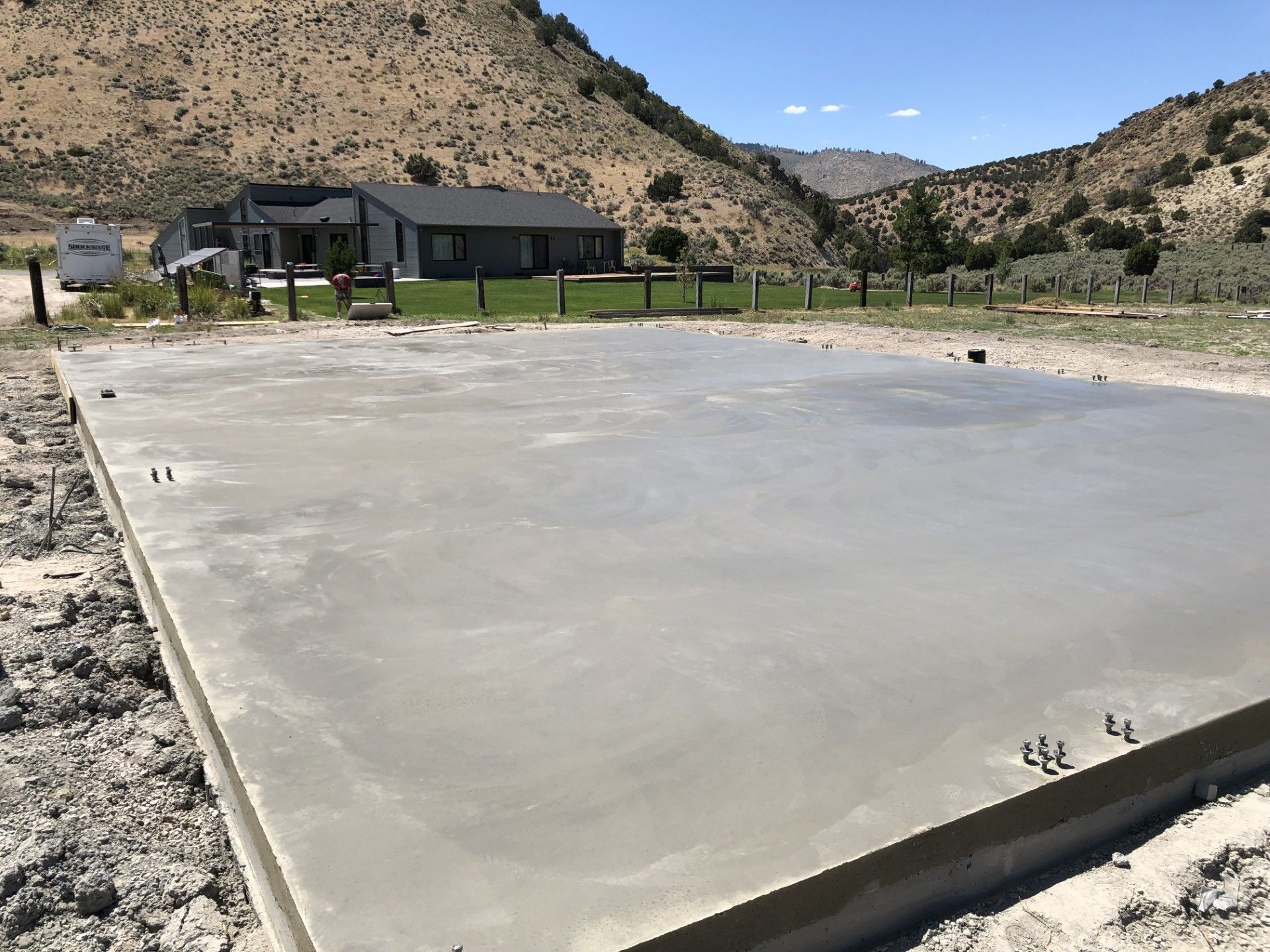 Fresh concrete slab in a desert setting with a house and mountains in the background