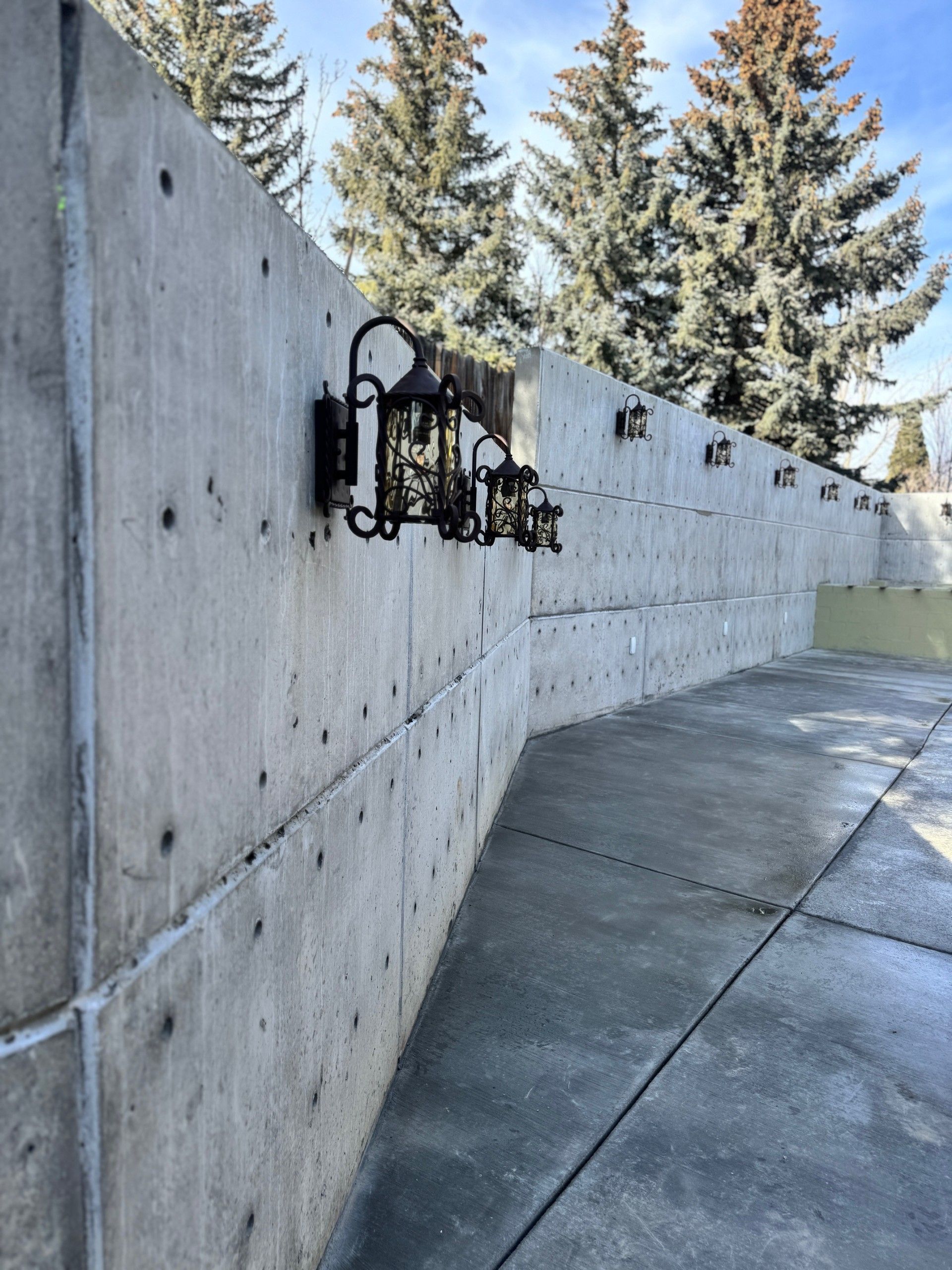 Snowy concrete wall with a black lantern and evergreen trees in the background