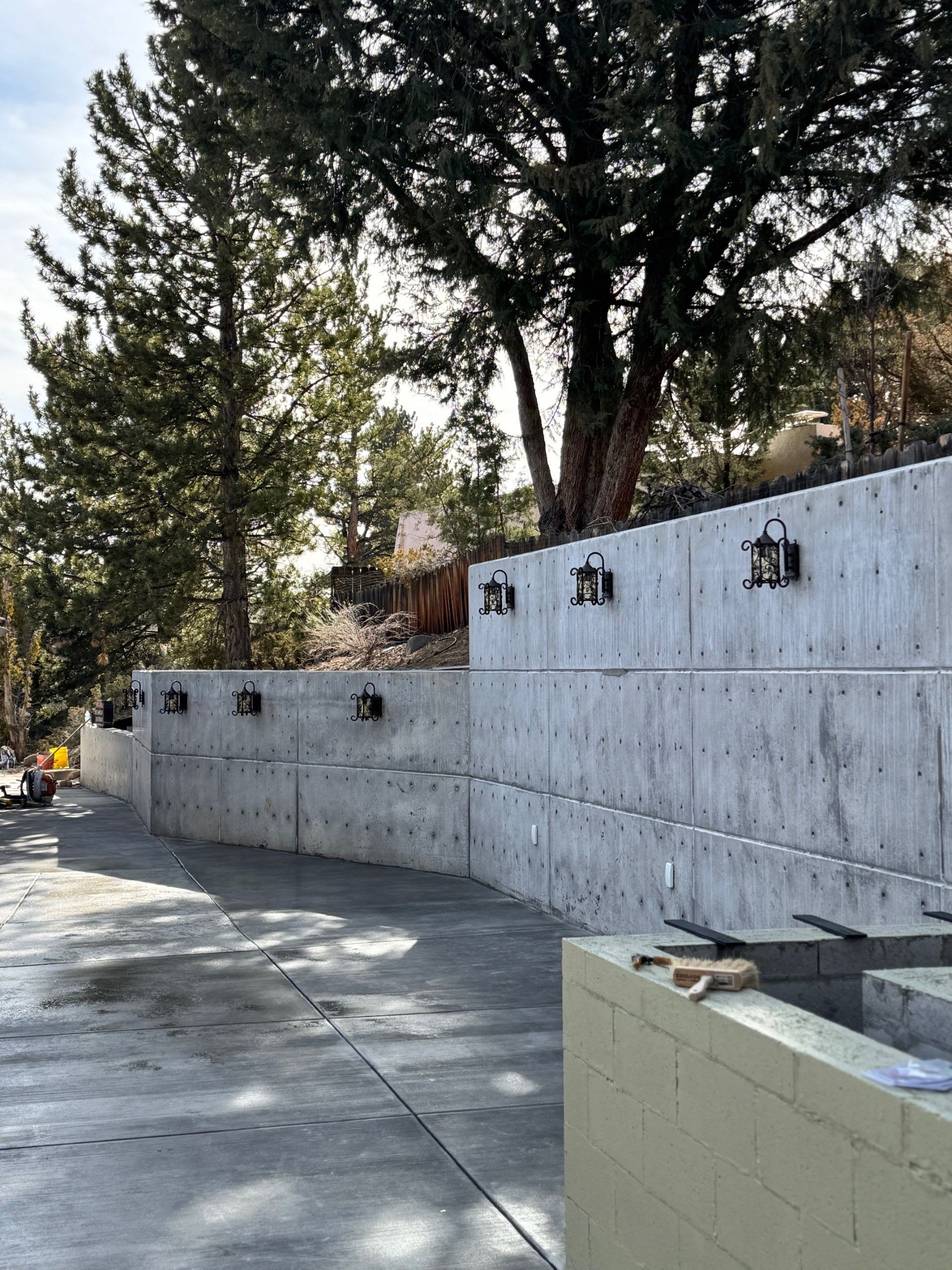 Concrete retaining wall along a tree-lined walkway in bright daylight