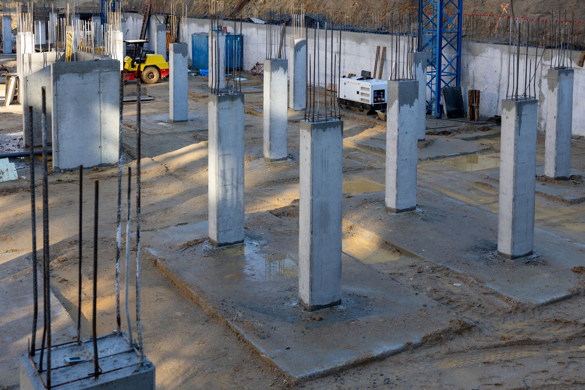 Construction site with concrete pillars and rebar columns in a partially built foundation