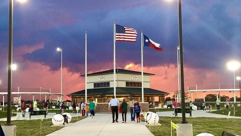 A group of people are walking in front of a building with flags flying in the wind.