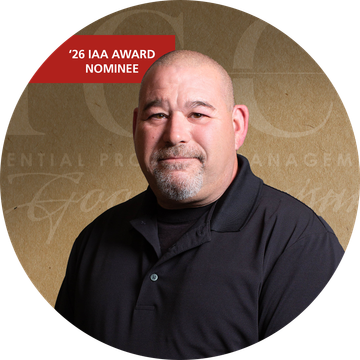 Bald man with a goatee wearing a black polo shirt in front of a neutral backdrop.
