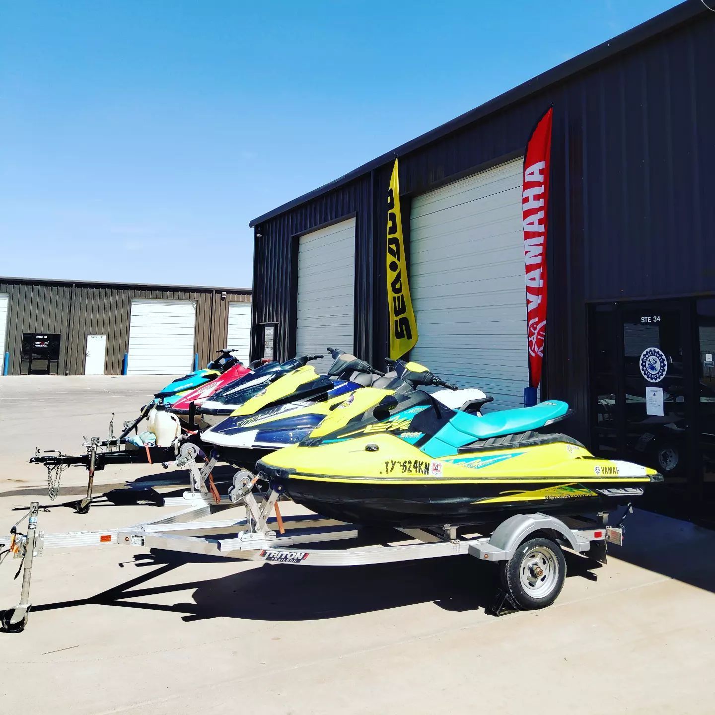 A row of jet skis are parked in front of a yamaha building.