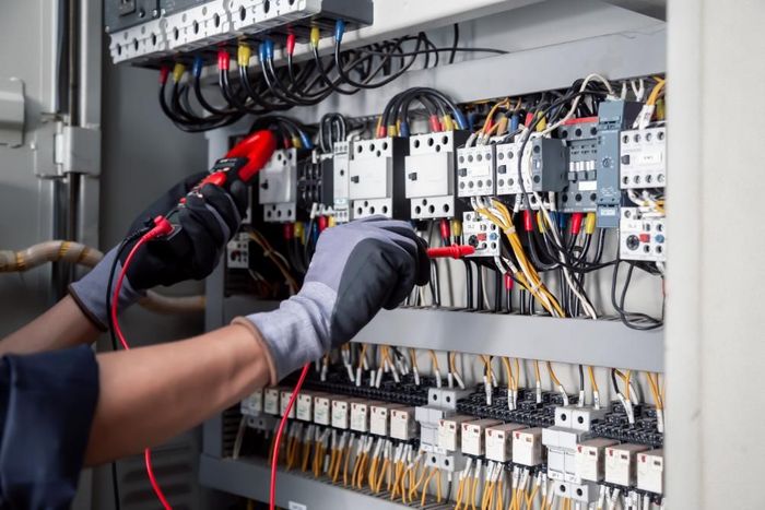 Technician testing wiring in an electrical control panel with a multimeter