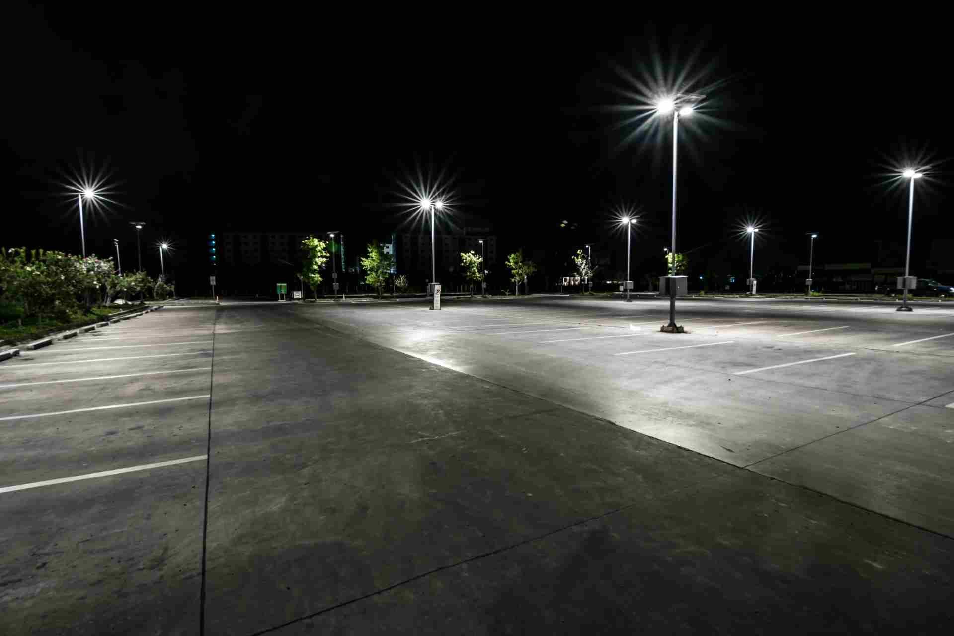 Empty, illuminated parking lot at night with tall street lights.