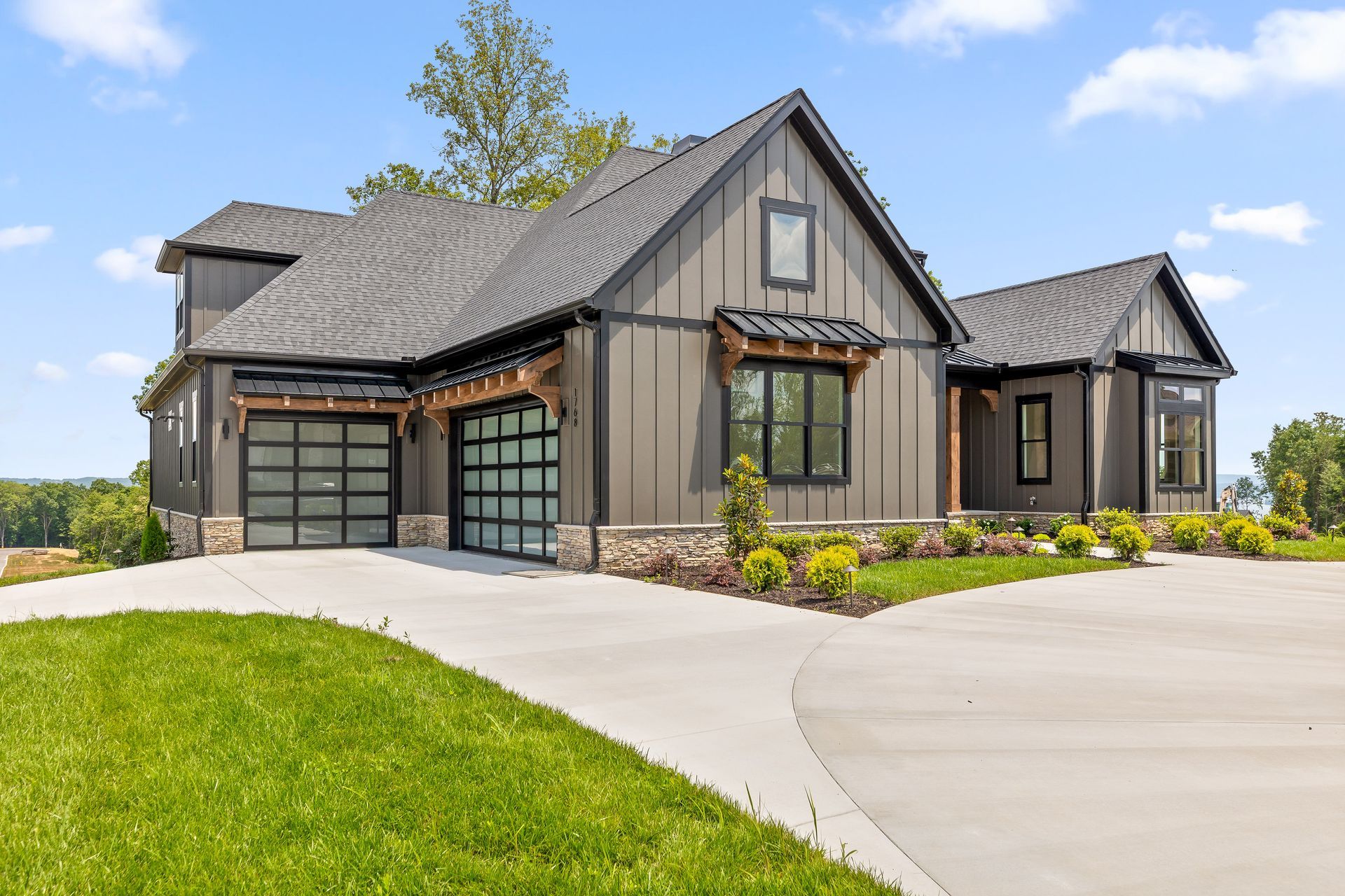 Modern gray house with a double garage, large windows, and a curved driveway. This is a custom home built by Nu-Era Construction in the neighborhood Serenity Cove in Soddy Daisy Tn
