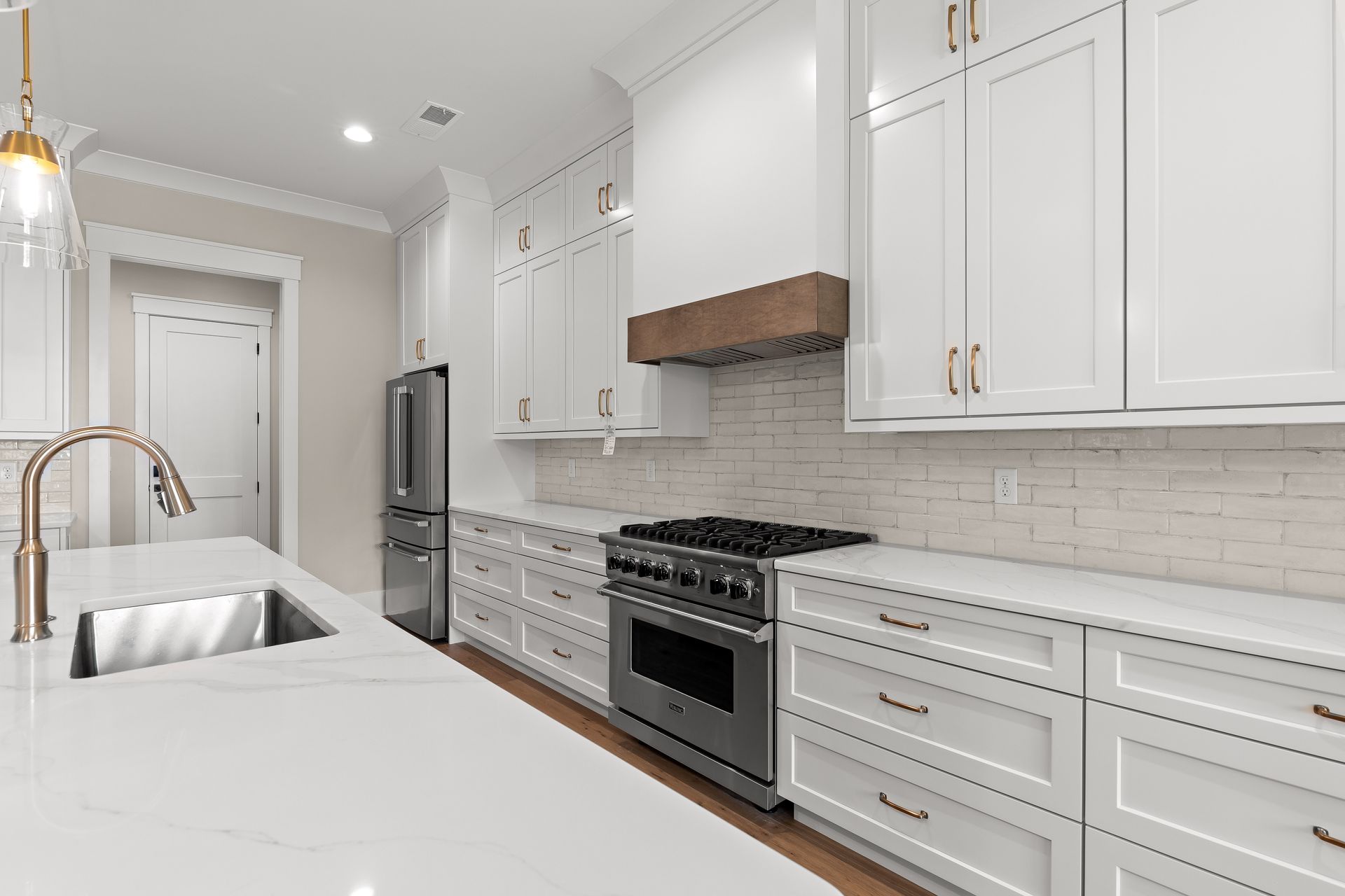 Bright white modern kitchen with marble island, stainless steel appliances, and white cabinetry