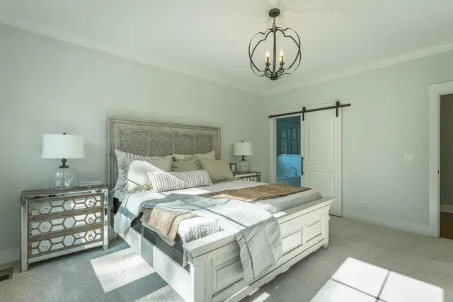 a bedroom with a bed , nightstands , lamps and a sliding barn door .