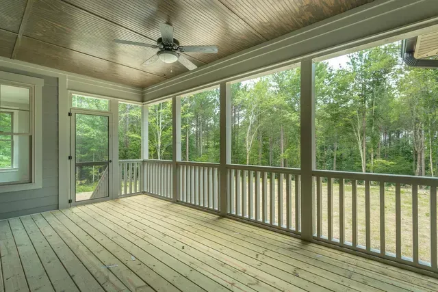 a screened in porch with a ceiling fan and lots of windows .
