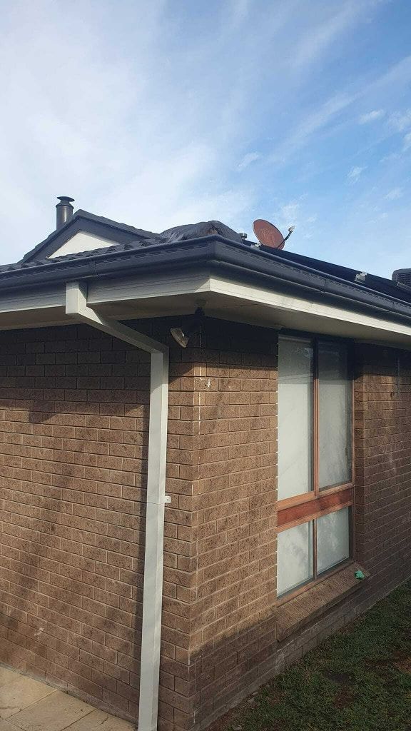 Brick House Exterior With Dark Roof, Satellite Dish, and Cloudy Sky  — The Roofer Troopers in Howlong, NSW