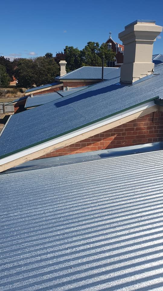 Corrugated Metal Roofs and Brick Building With Chimneys — The Roofer Troopers in Howlong, NSW