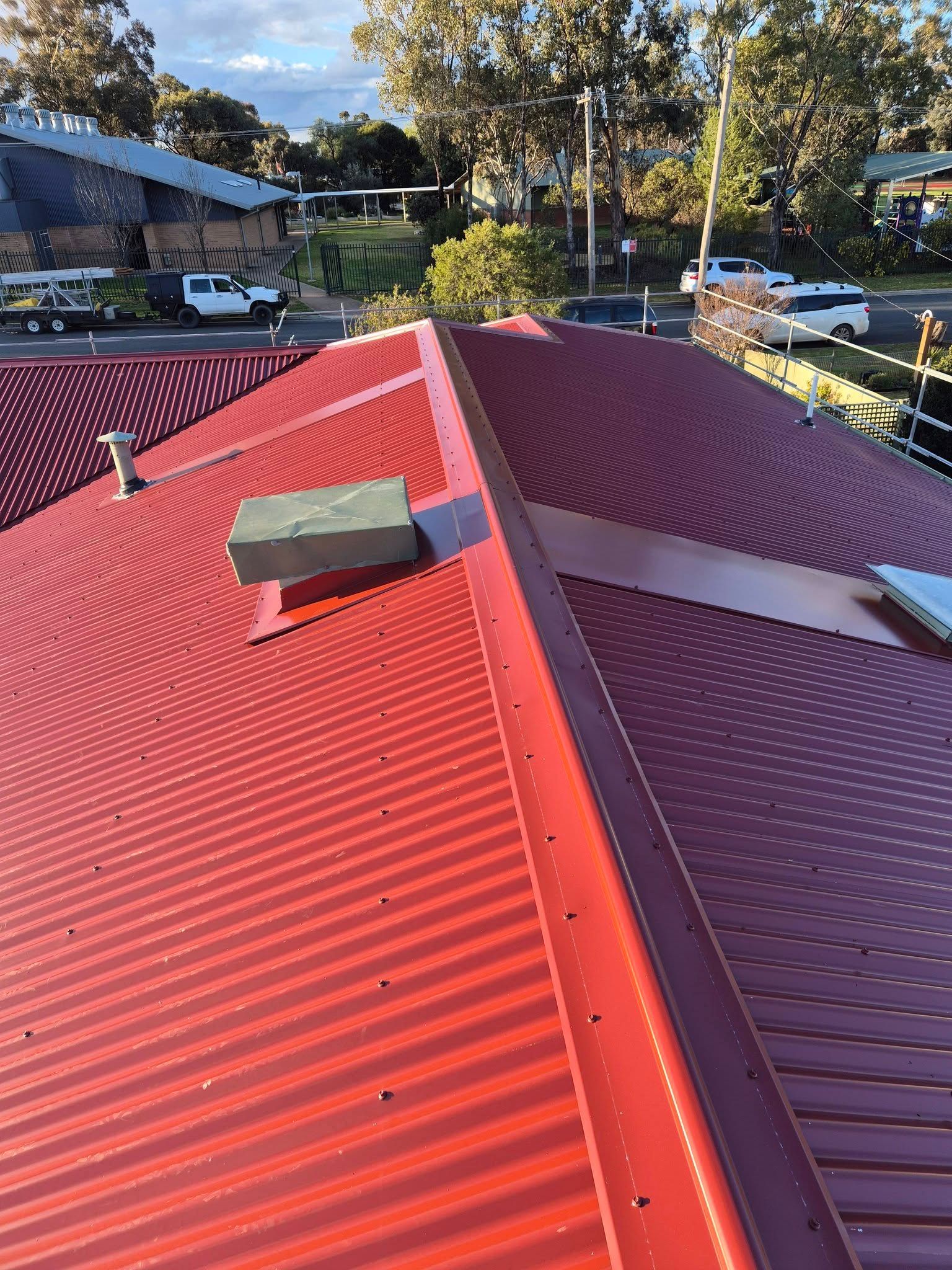 Roofing In Albury Red Colorbond Roof With Ridge Capping, Vents And Skylights On A Residential Home
