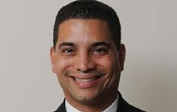 Smiling man in a dark suit against a light gray background