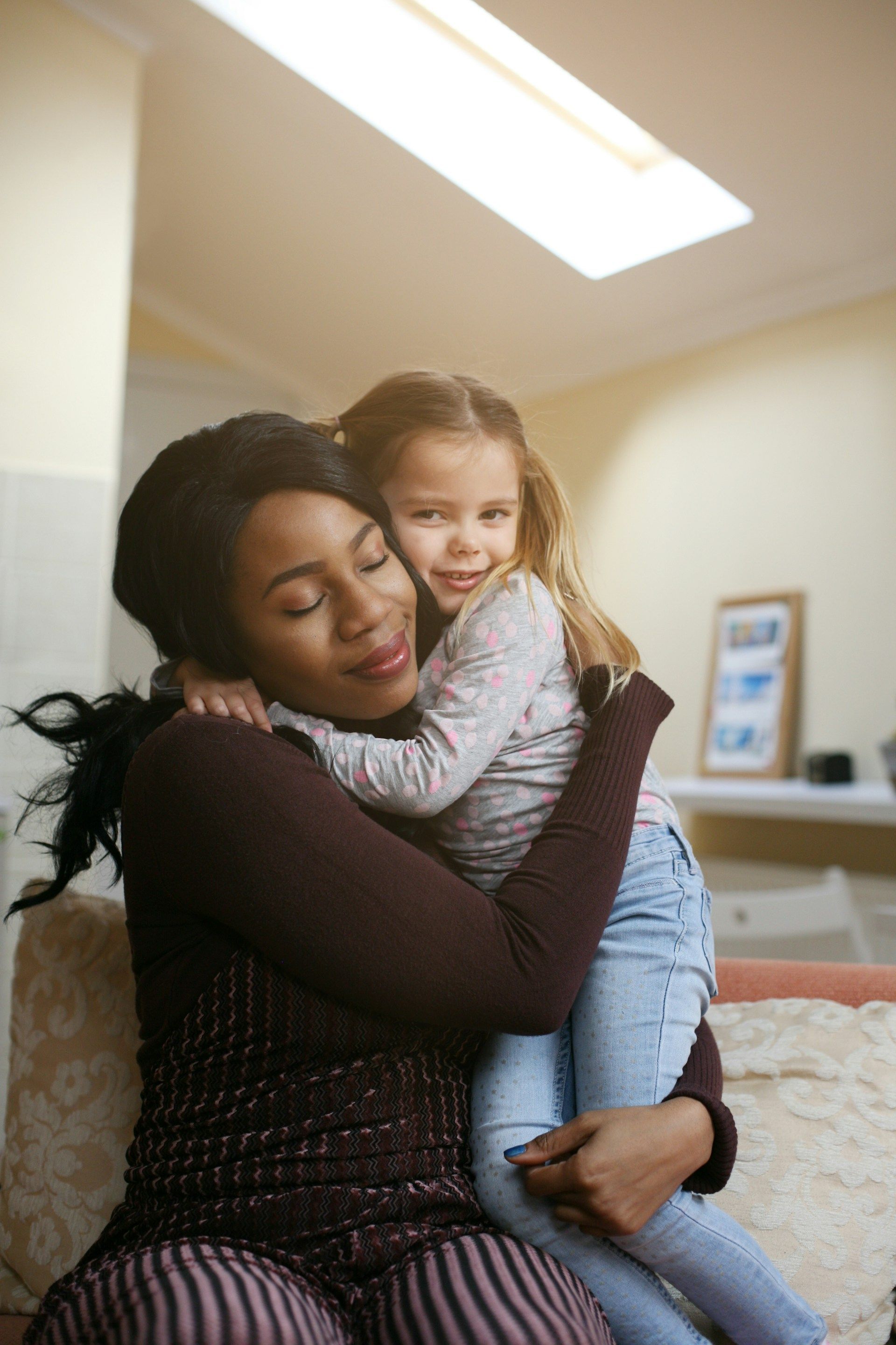Two people hugging on a couch in a bright living room