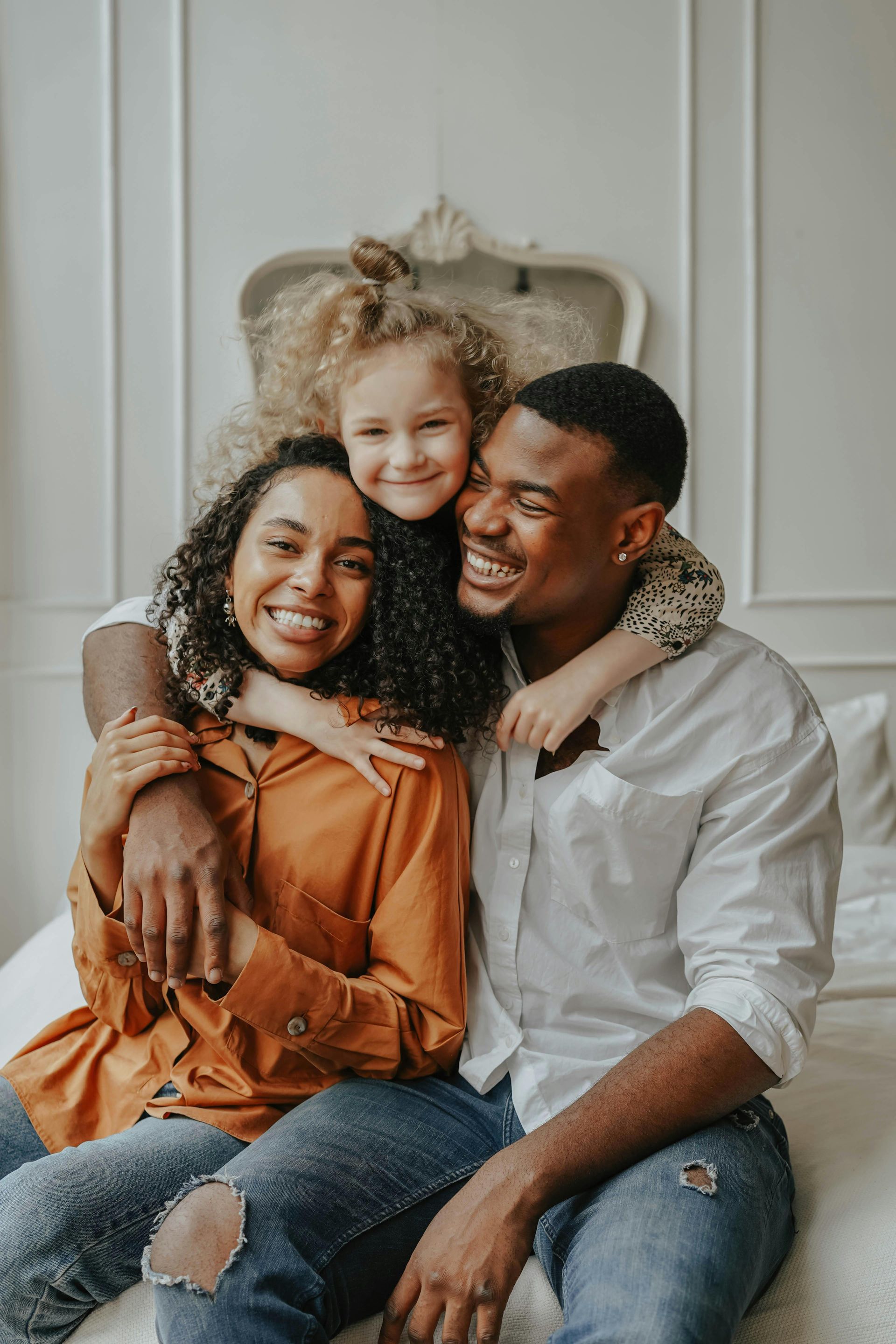 Three people smiling and hugging on a couch in a bright room
