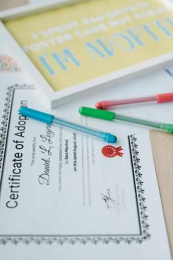 Adoption certificate with colorful pens on a desk, suggesting paperwork being signed or filled out