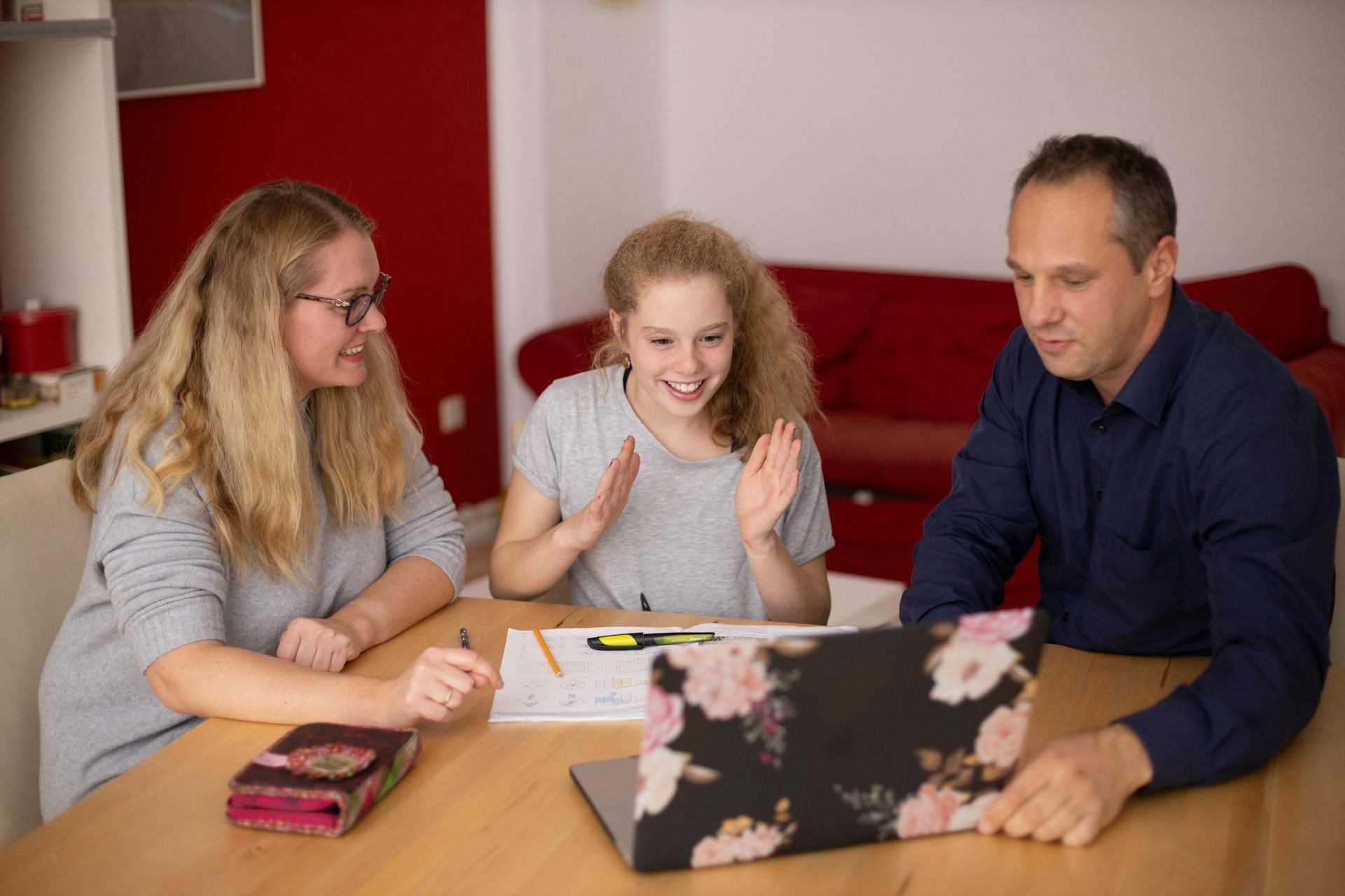 Three people collaborating at a table with a laptop in a living room