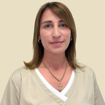Foto Teammitglied Frau in beigefarbener Kasack und Kette, lächelnd, in einem runden Rahmen vor neutralem Hintergrund.