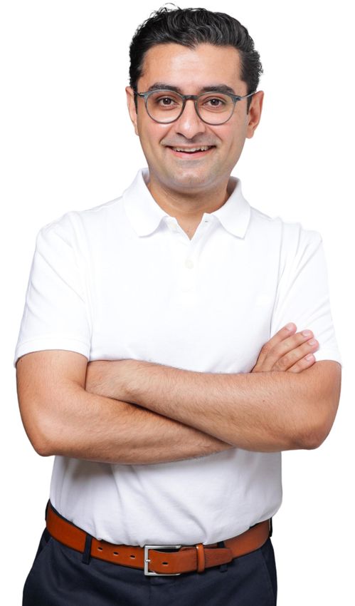 Portrait Dr Schapoor Hessam Dr. Hessam mit Brille, verschränkten Armen, in einem weißen Poloshirt und dunkelblauer Hose. Lächelt.