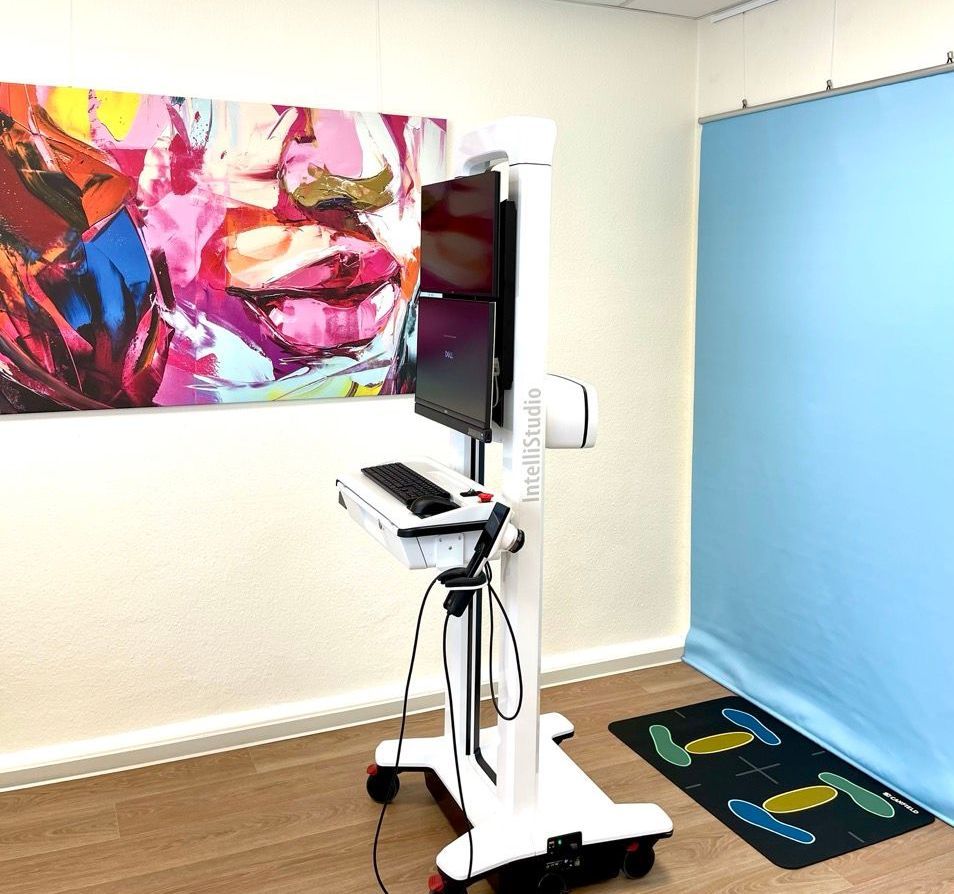 Ein Untersuchungsraum mit dem Gerät Total Body Mapper und blauem Hintergrund. Kunstwerke an der Wand.
