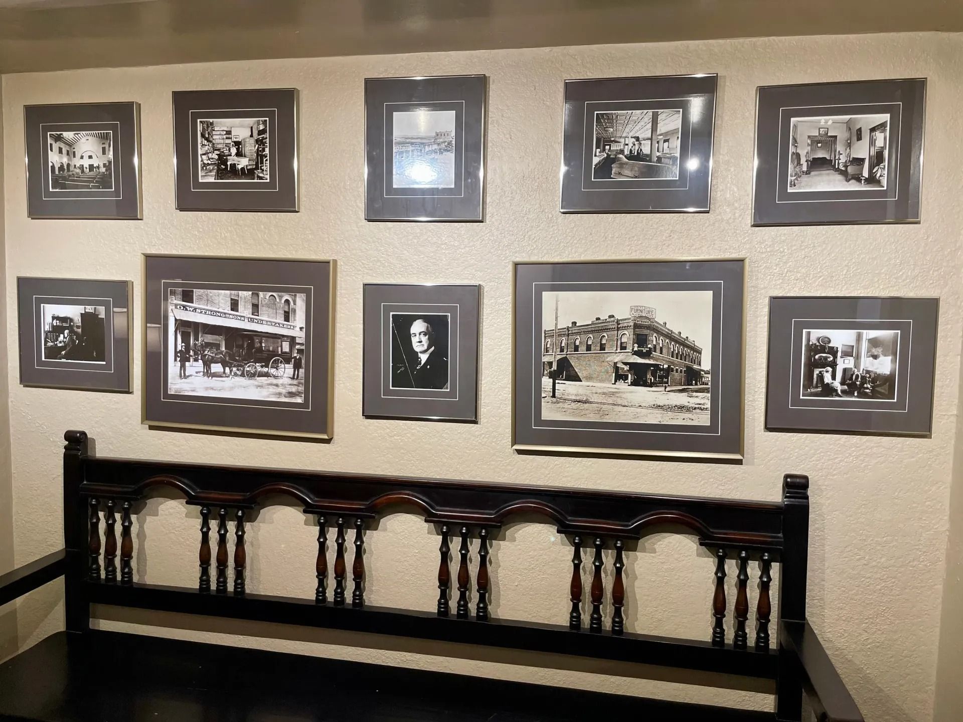 Gallery wall of framed black and white photos above a dark wood bench.