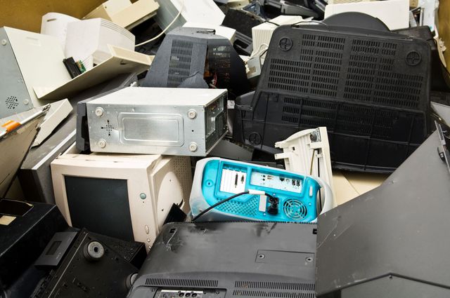 Heap of old computer monitors, towers, and other electronic waste in a container.
