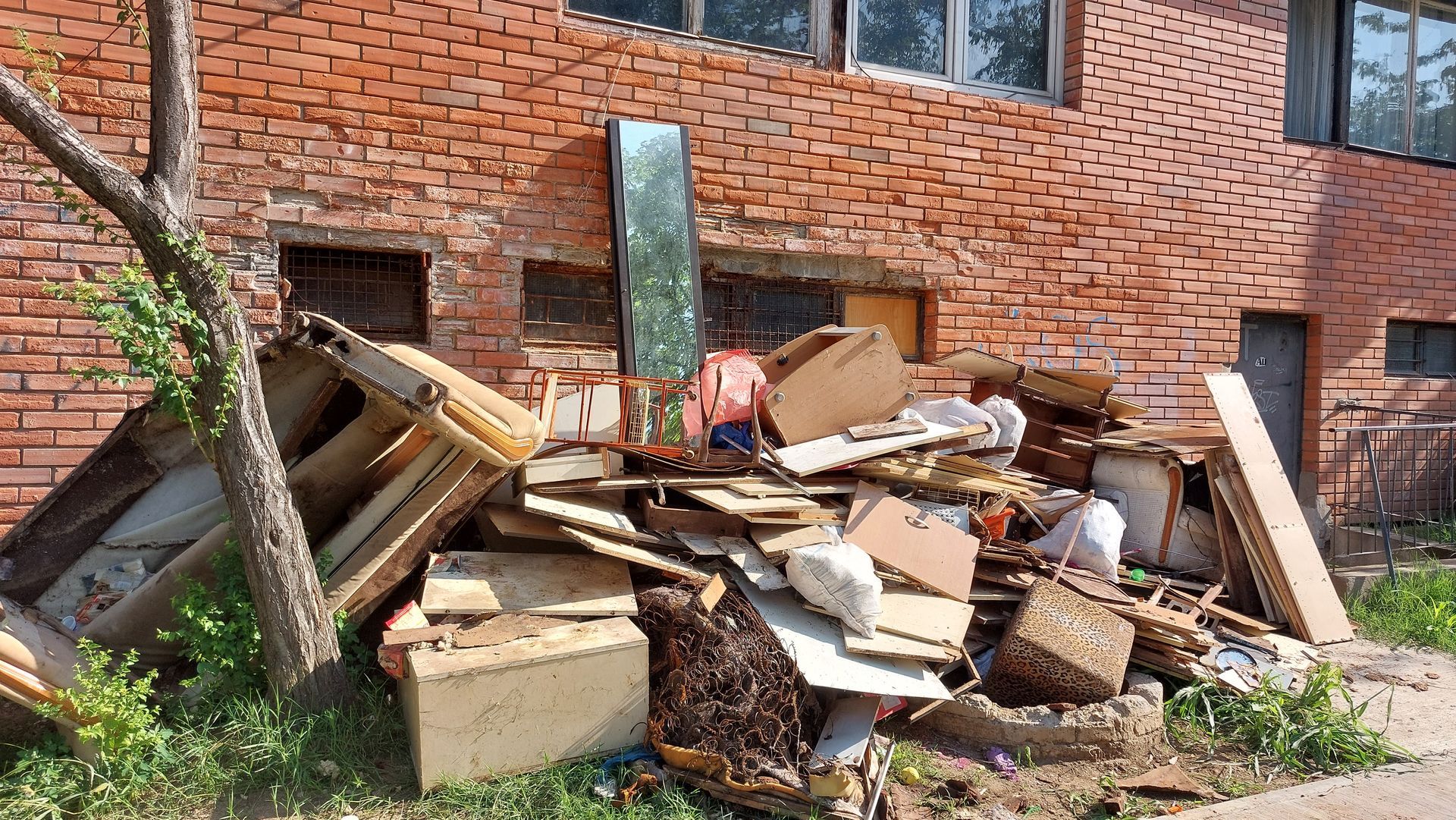 Pile of debris, including wood and cardboard, in front of a red brick building.