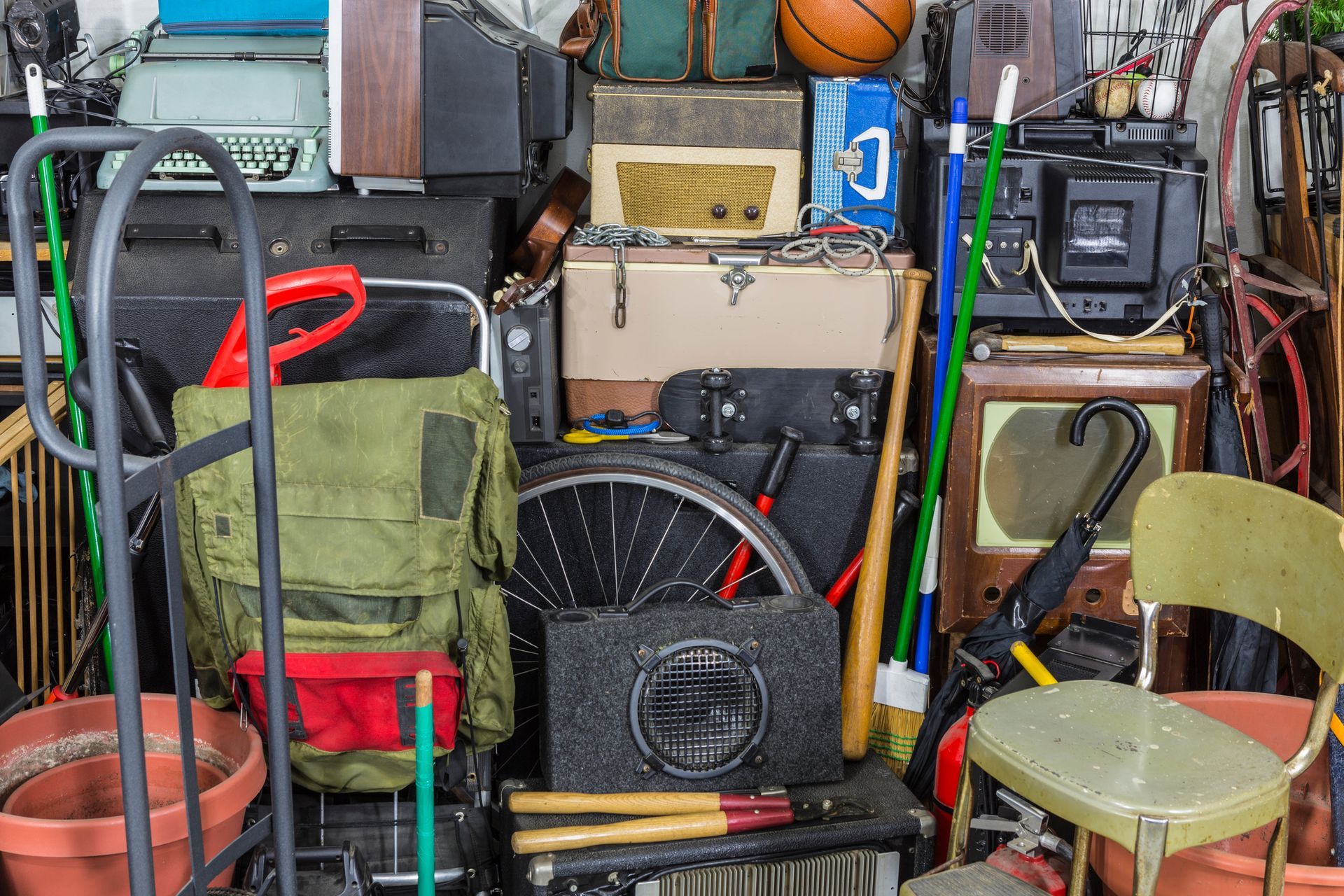 Cluttered garage with various items: boxes, tools, equipment, and a basketball.