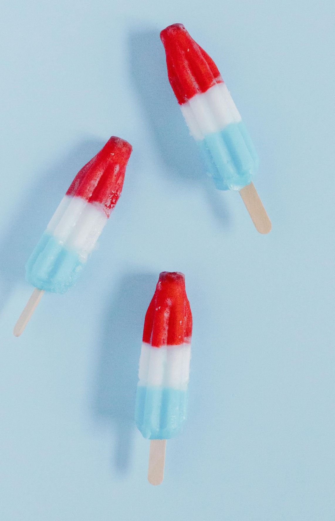 Three red, white, and blue popsicle treats on a light blue background.