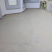 Concrete porch with a light gray door, white railing, and a small deck area.