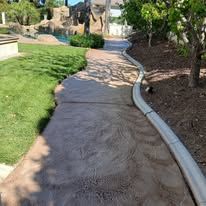 Curved stamped-concrete walkway beside grass and trees in a landscaped park area