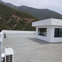 Rooftop terrace of a modern white building with mountain hills in the background