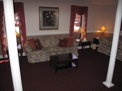 Living room with floral sofas, lamp tables, framed art, and dark carpet in a cozy interior.